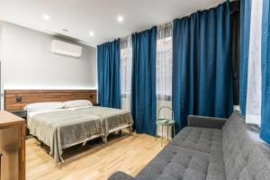 VR LATINA APARTMENTS في مدريد: غرفة نوم بسرير واريكة وستائر زرقاء