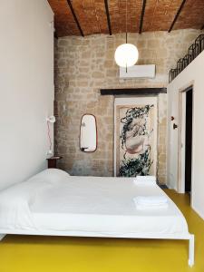 a bedroom with a white bed and a brick wall at Magma Home - Rooms & Roof in Naples