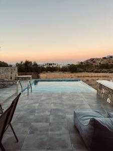 - une piscine avec 2 chaises sur la terrasse dans l'établissement Eleon Luxury Villa, à Karpathos