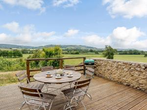 um pátio com uma mesa e cadeiras num deque de madeira em 3 bed in Lyme Regis OXENL em Kilmington