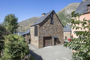 an old stone building with a garage in front of a mountain at Luderna - Casa Carboneu in Naut Aran