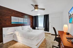 a bedroom with a large white bed and a desk at Waves Beach Town Studio Apartment in Pompano Beach