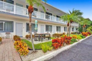 a building with a patio with a table and palm trees at Waves Beach Town Studio Apartment in Pompano Beach