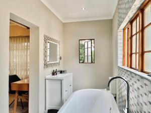 a white bathroom with a tub and a sink at The Stella Guest House & Spa in Ermelo