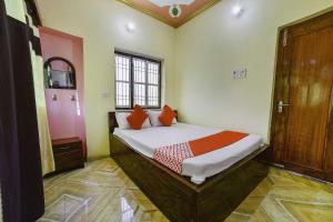 1 dormitorio con 1 cama con almohadas de color naranja en OYO Flagship Ashoka Guest House, en Bihta