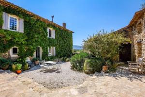 un jardín con mesa y sillas frente a un edificio en le mas du lavoir, en Gordes