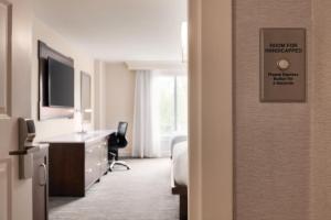 a hotel room with a bed and a desk and a room with a sign at Hilton Naples in Naples