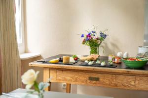 Hotel Tafelfreuden في أولدنبورغ: طاولة مع صحن من الطعام و مزهرية من الزهور