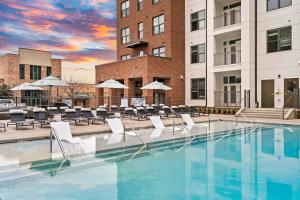 a pool with chairs and umbrellas in front of a building at Mint House Greenville - West End in Greenville