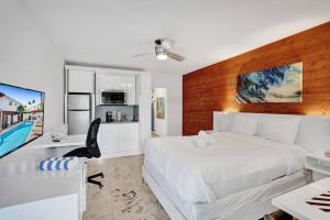 Schlafzimmer mit einem großen weißen Bett und einem Schreibtisch in der Unterkunft Waves Beach Town Cozy Studio Apartment in Pompano Beach