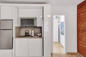 eine weiße Küche mit einer Spüle und einer Mikrowelle in der Unterkunft Waves Beach Town Cozy Studio Apartment in Pompano Beach