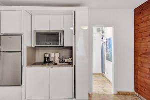 a white kitchen with a sink and a microwave at Waves Beach Town Cozy Studio Apartment in Pompano Beach
