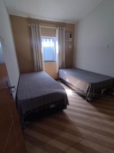 two beds in a small room with a window at Casa no Centro de Prado in Prado