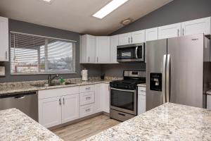 a kitchen with white cabinets and stainless steel appliances at Mountain Views minutes from casinos and Lake in Bullhead City