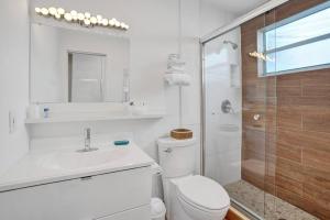 a bathroom with a toilet and a sink and a shower at Waves Beach Town 2BR Apartment in Pompano Beach +16 photos