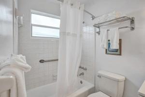 a white bathroom with a toilet and a shower at Waves Beach Town Spacious Studio Apartment For 4 People in Pompano Beach
