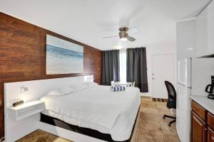 a bedroom with a white bed and a refrigerator at Waves Beach Town Cozy Studio Apartment in Pompano Beach
