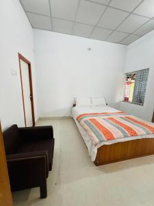 a bedroom with a bed and a chair in it at Fairy Hills ( Cottage & Park ) in Sreemangal