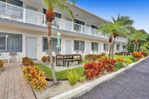 a building with a patio with a table and palm trees at Waves Beach Town Cozy Studio Apartment in Pompano Beach