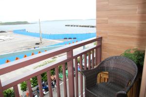 einen Balkon mit einem Stuhl und Blick auf das Wasser in der Unterkunft Luck Bay B&B in Magong