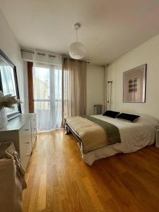 a bedroom with a bed and a large window at Les temps heureux 15' Paris 10' du Stade de France in Saint-Denis