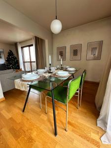 a dining room with a glass table and green chairs at Les temps heureux 15' Paris 10' du Stade de France in Saint-Denis