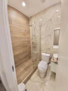uma casa de banho com um WC e uma cabina de duche em vidro. em Real City Suites Syntagma em Atenas
