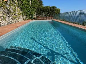 a swimming pool with blue water and a fence at Unique, waterfront Villa la Madonnina for 6, waterfront, pool, parking in Furore