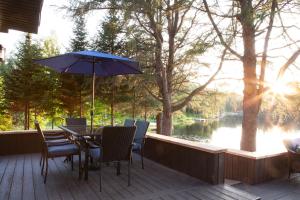 a patio with a table and chairs and an umbrella at Bleu Azur 32 night Lakefront Retreat w Hot tub in Saint Adolphe D'Howard