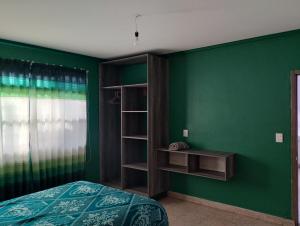 Dormitorio con paredes verdes, cama y estante en Casa mami2, en Oaxaca City