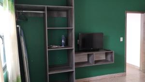un estante de libros con TV y pared verde en Casa mami2, en Oaxaca City