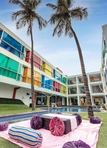 a hotel with palm trees and a table with colorful pillows at I Love Bell Bottoms Vagator Goa in Anjuna