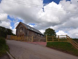 a barn with a wooden fence next to a road at 2 Bed in Chulmleigh 72791 in Coldridge