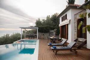 a patio with a pool and chairs next to a house at Elia Pilio Villas in Pilion