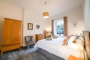 a bedroom with a bed and a chair and a window at Dales View Cottage in Sedbergh