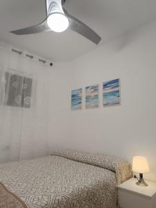 a white bedroom with a bed and a ceiling fan at El Yate Sol y Mar in Aguadulce