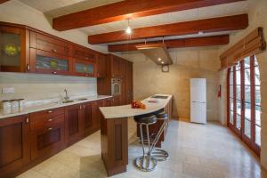 a large kitchen with wooden cabinets and a white refrigerator at 5 Bedroom Farmhouse with Private Pool & Views in Għarb