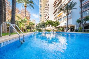 a swimming pool with palm trees and buildings at Edimar 2-3 Apartment Levante Beach in Benidorm