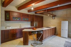 - une cuisine avec des placards en bois et un réfrigérateur blanc dans l'établissement 5 Bedroom Farmhouse with Private Pool & Views, à L-Għarb
