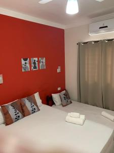 a bedroom with a white bed and a red wall at Pousada Recanto Som do Mar in Caraguatatuba