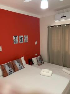 sypialnia z białym łóżkiem i czerwoną ścianą w obiekcie Pousada Recanto Som do Mar w mieście Caraguatatuba
