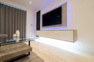 Luxury, Modern & Cosy 1 Bedroom Prestige London Apartment في لندن: غرفة معيشة مع تلفزيون وطاولة زجاجية