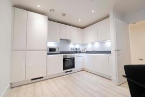 a white kitchen with white cabinets and appliances at Luxury, Modern & Cosy 1 Bedroom Prestige London Apartment in London
