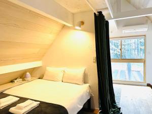 - un petit lit dans une chambre avec fenêtre dans l'établissement Hakuba Bliss Cottage - Vacation STAY 28524v, à Hakuba