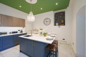 uma cozinha com armários azuis e um tecto verde em The Steam House - 3 Bedroom Townhouse in Bath by Mint Stays em Bath