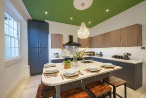 uma cozinha com armários azuis e uma mesa com cadeiras em The Steam House - 3 Bedroom Townhouse in Bath by Mint Stays em Bath