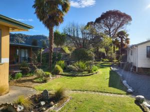 a yard with a palm tree and a house at Off The Beaten Trail Acc & Bike Tours in Murchison