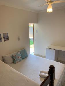 1 dormitorio con 1 cama blanca y ventilador de techo en Pousada Recanto Som do Mar, en Caraguatatuba
