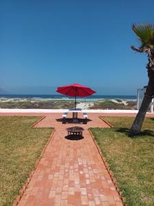 una mesa de picnic con una sombrilla junto a la playa en Bungalos Las Esperanzas, en Cabo Punta Banda