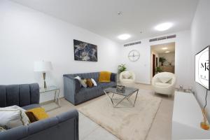 sala de estar con sofá azul y 2 sillas en Sunny Seaside 2 Bedroom Apartment, Dubai Marina en Dubái